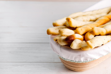 Traditional Italian bread sticks with poppy in a basket on a white wooden background.