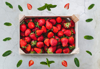 Flat lay basket of fresh strawberries on marble and mint background