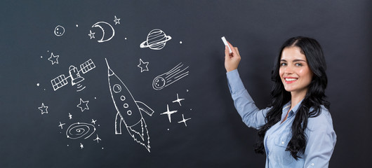 Dream of space and rocket with young woman writing on a blackboard