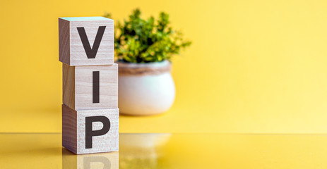 Word VIP made with wood building blocks on a light yellow background