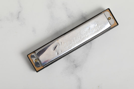 Harmonica isolated on white marble background .silver