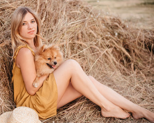 Beautiful girl near a hay bale with a dog. Girl on the background of haystack © Ксения Пальчик