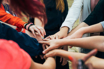 Several people of different ages folded their hands on each other. Team building exercise. Unity,...