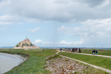 Fototapeta na wymiar group of people on horseback making their way towards Mont Saint-Michel with 