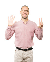 Happy young man doing a number seven gesture with his hands