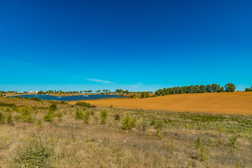 Obraz premium field country side scenery environment with solar system factory far on horizon background line end of summer season August