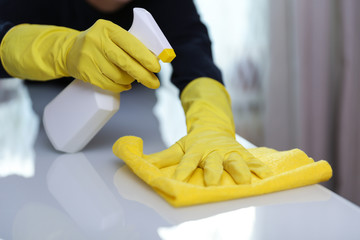 cleaner's hands in yellow rubber gloves doing disinfection cleaning with detergent spray and rag. preventive measures against virus infection