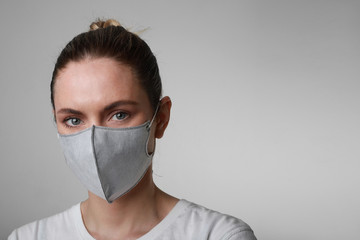 Portrait of young woman in medical face protection mask indoors on white background. Protection of the virus.