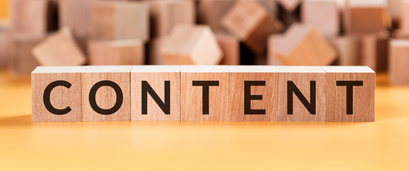 Word content on wooden cubes on a yellow background with blurred cubes.