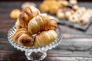 Fresh croissants in glass bowl on wooden background