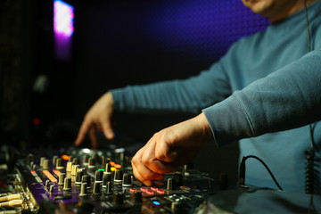 dj hands playing music on turntable close up. dj's hand is mixing tracks at party in night club.