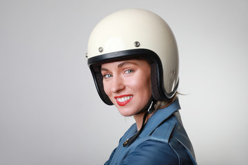 Close-up portrait of happy biker young woman, wearing retro helmet, with red lips. Space for your text.