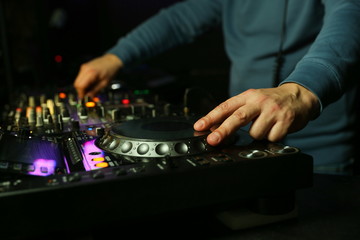 dj hands playing music on turntable close up. dj's hand is mixing tracks at party in night club.