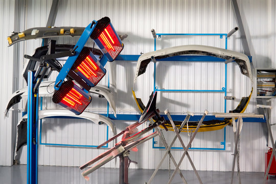 Painting And Drying Under Lamps In Professional Box Of Car Body Parts After Applying Putty And Paint On Bumper