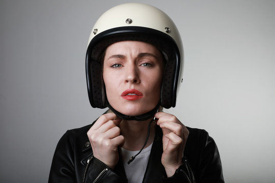 Close-up portrait of serious biker young woman, wearing retro helmet, with red lips. Space for your text.
