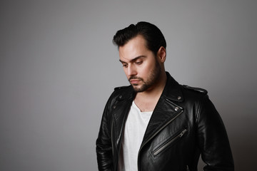 Obraz premium Portrait of modern young hipster man in a leather stylish jacket posing over a white background.