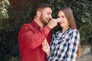 Fototapeta premium Cute couple in a park. Lady with ice cream. Guy in a red shirt