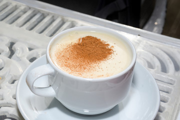 white cup of salep milky hot drink of Turkey with cinnamon powder and sticks healthy spice
