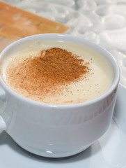 white cup of salep milky hot drink of Turkey with cinnamon powder and sticks healthy spice