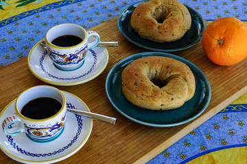 Fresh baked Italian donuts and espresso coffee in stylish cups on colorful tablecloth.