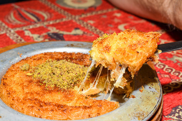 Turkish dessert kunefe with pistachio powder. Kunafa, kadayif with pistachio powder and cheese hot