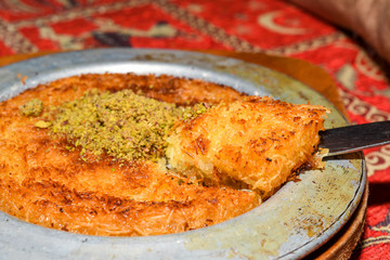 Turkish dessert kunefe with pistachio powder. Kunafa, kadayif with pistachio powder and cheese hot