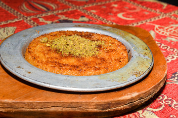 Turkish dessert kunefe with pistachio powder. Kunafa, kadayif with pistachio powder and cheese hot