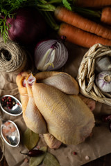 Fresh raw French chicken coquelet on a table with vegetables