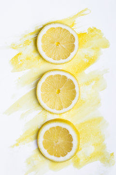 Top view of three lemon pieces on white paper with yellow watercolor