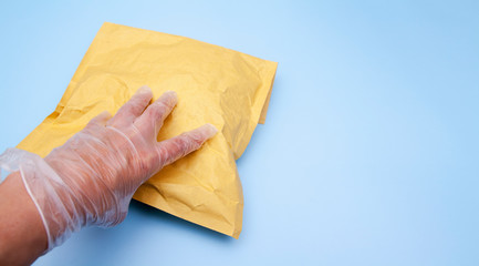 A gloved hand holds a craft package. Safety delivery of goods during quarantine of the coronavirus. Copy space