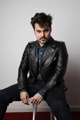 Vertical shot of modern stylish young hipster man in a leather jacket posing over a white background. Isolated.