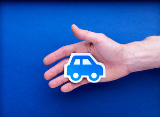 Illustration de voiture en papier au creux d'une main d'homme sur fond bleu