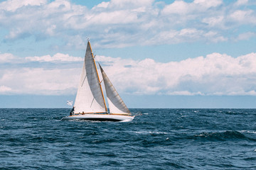A sailing boat navigating in front of Barcelona coast line during a stormy winter afternoon.