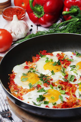 Shakshouka with five cooked eggs on top of tomato sauce in cast iron skillet