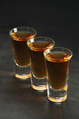 Three shots with whiskey at dark background