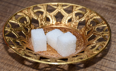 Fototapeta na wymiar Three white sugar cubes isolated on goden turkish plate, for morning coffee sweetener.