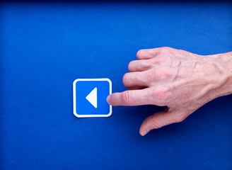 Un pictogramme imprimé de bouton play sur lequel une main d'homme clique, sur fond bleu