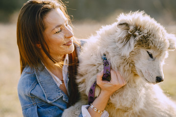 Woman in a spring forest. Girl with cute dog. Brunette in a jeans jacket.