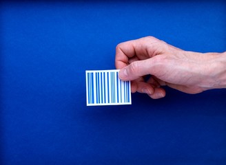 Code barre saisi par une main sur fond bleu pour illustration commerce, retail, e-business, vente,...