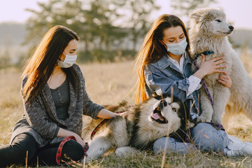 Women in a masks in a spring forest. Girls with cute dogs. Corona virus.