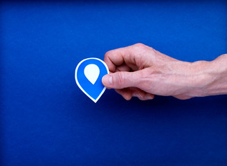 Illustration dessin picto localisation géographique tenu par une main d'homme isolé sur fond bleu