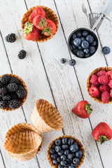 A top down view of waffle bowls filled with various berries and copy space in the middle.