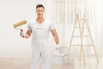 Painter holding a paint roller and a color bucket in a room