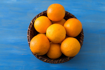 Fresh oranges in the wicker basket on the ground.