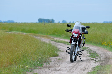 Fototapeta na wymiar Motocicleta en camino de tierra en medio del campo