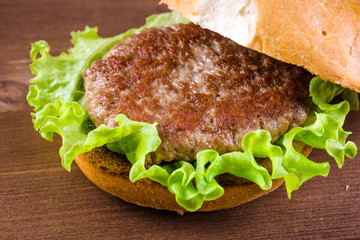 Cooking a delicious homemade burger, ingredients - fried bun, cutlet, lettuce, tomato, onion and sauce