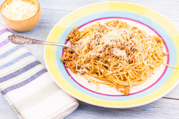 Plate with a portion of spaghetti bolognese and grated cheese close-up - traditional Italian cuisine