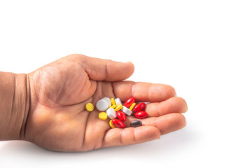 Many tablets of various medicinal drugs in human hand on white background.