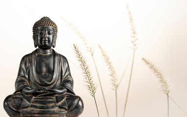 A view of a replica statue of The Buddha with fountain grass in the background