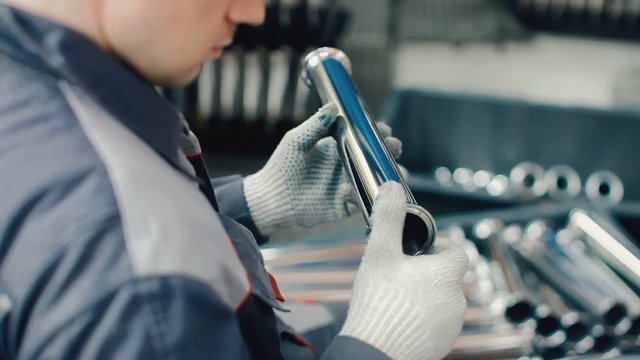 Worker holding steel tube in hands. Factory workerman checking metal part for defects. Visual inspection of product quality. Quality control of factory part before using in production process